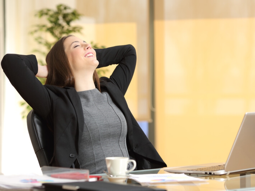 Happy executive woman breathing fresh air at her desk.jpg