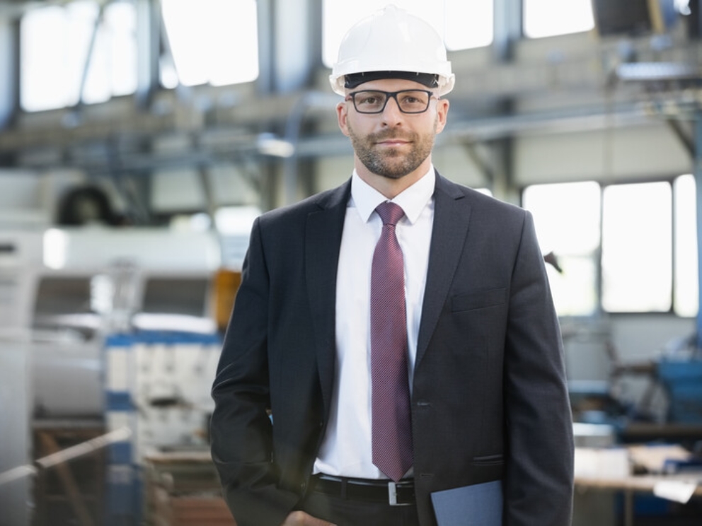 Portrait of confident mid adult businessman wearing hardhat in metal industry.jpg