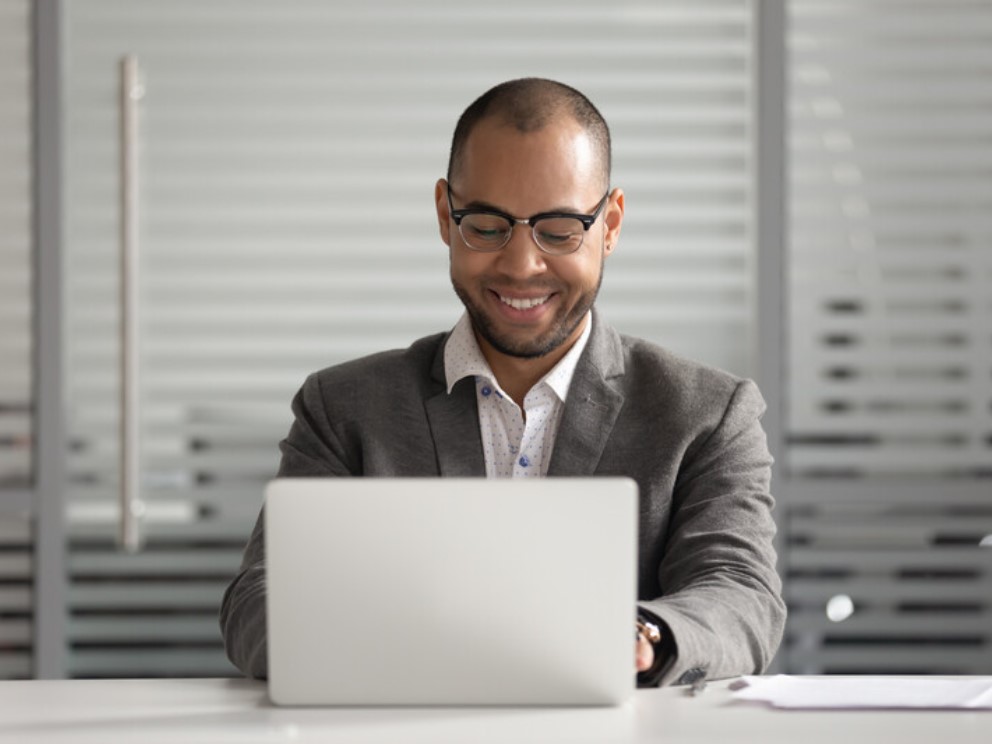 Smiling African American businessman using laptop, looking at screen.jpg