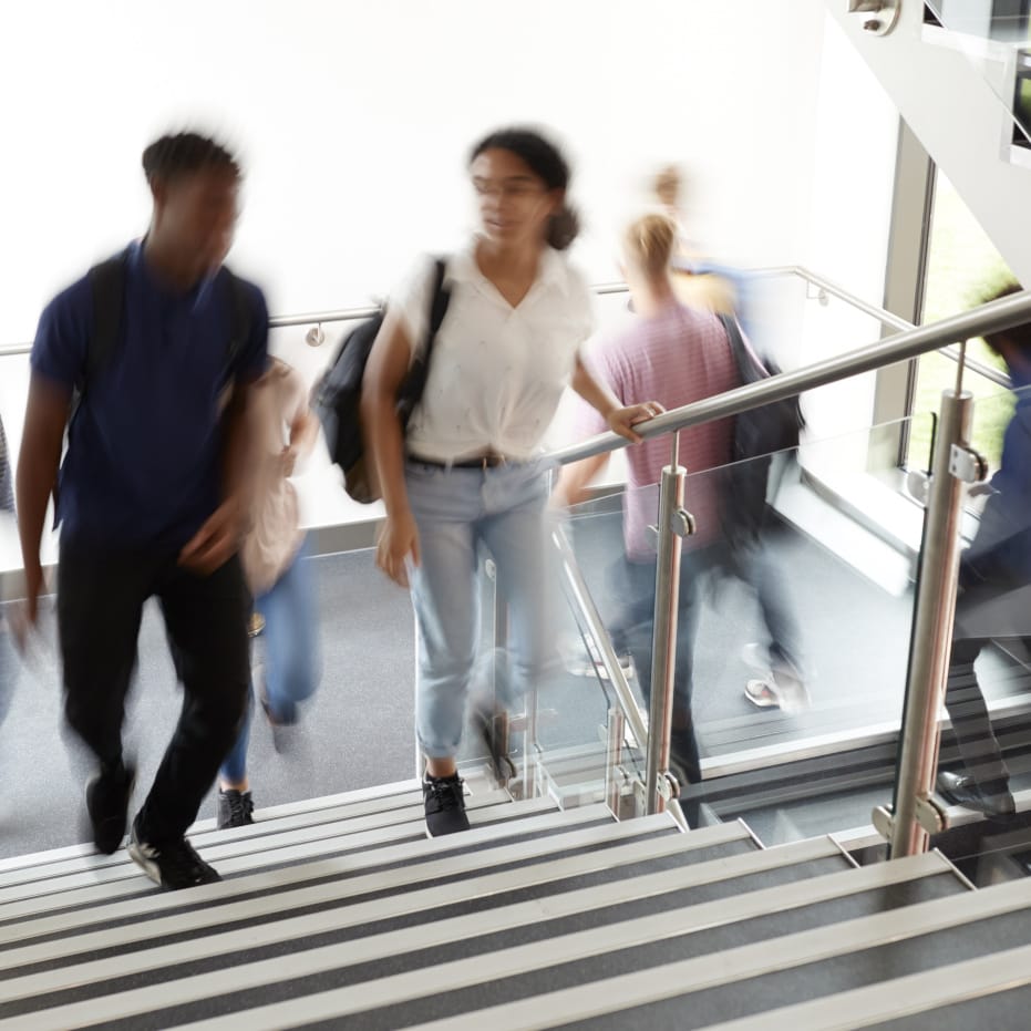 Motion Blur Shot Of High School Students Walking On Stairs Between Lessons In Busy College Building